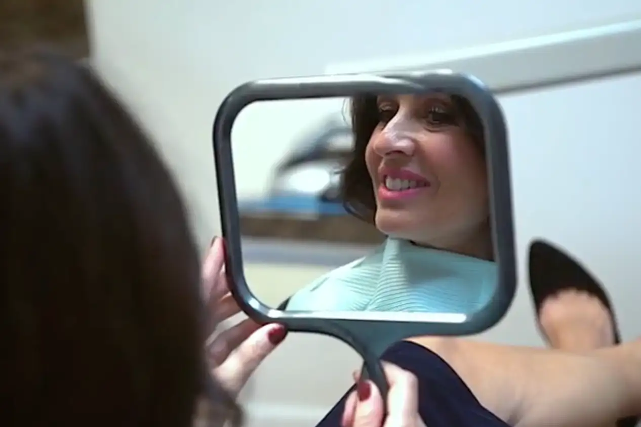 A woman smiling in the mirror at Smile Makers Dental Center 