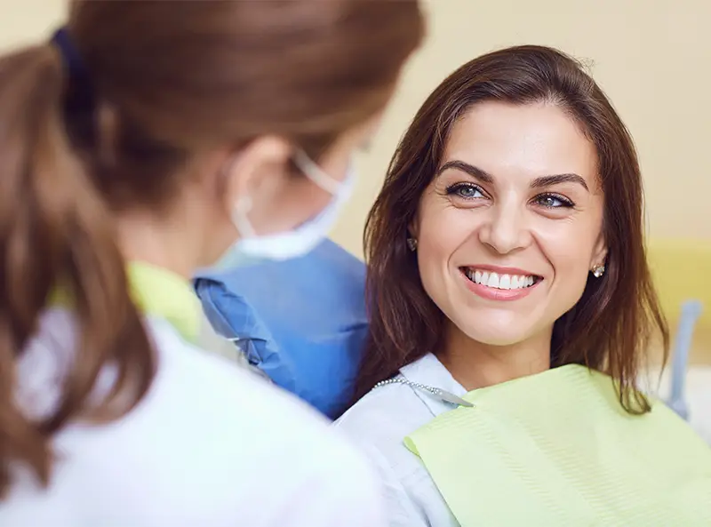 A happy patient in dental chair talking to her provider at Smile Makers Dental Center 