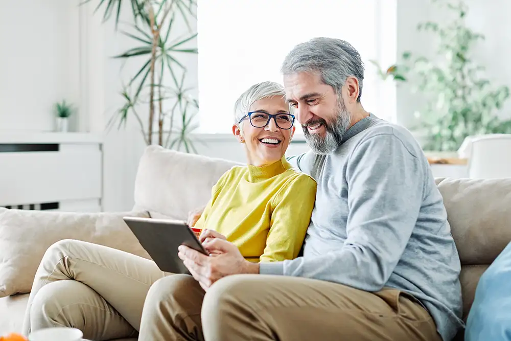 A couple looking at their ipad and smiling.