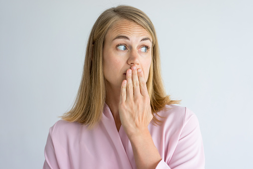 Woman holding her mouth over her funky breath