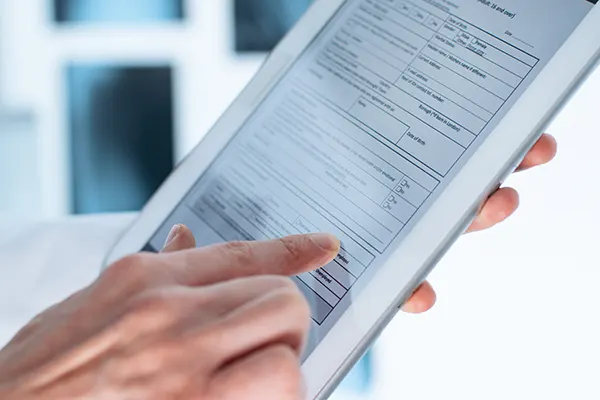 Close up of patient hands filling out patient forms on a tablet device.