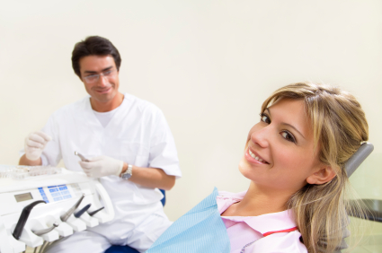 Blonde woman smiling in dental chair while Dentist is in the background