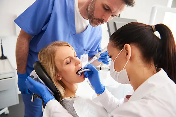 Dental team performing a root canal procedure on a patient in a modern dental office. 